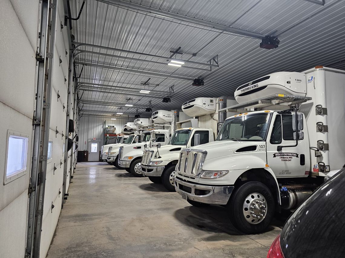Wenger Distributing company-owned fleet of refrigerated straight trucks lined up in the shop